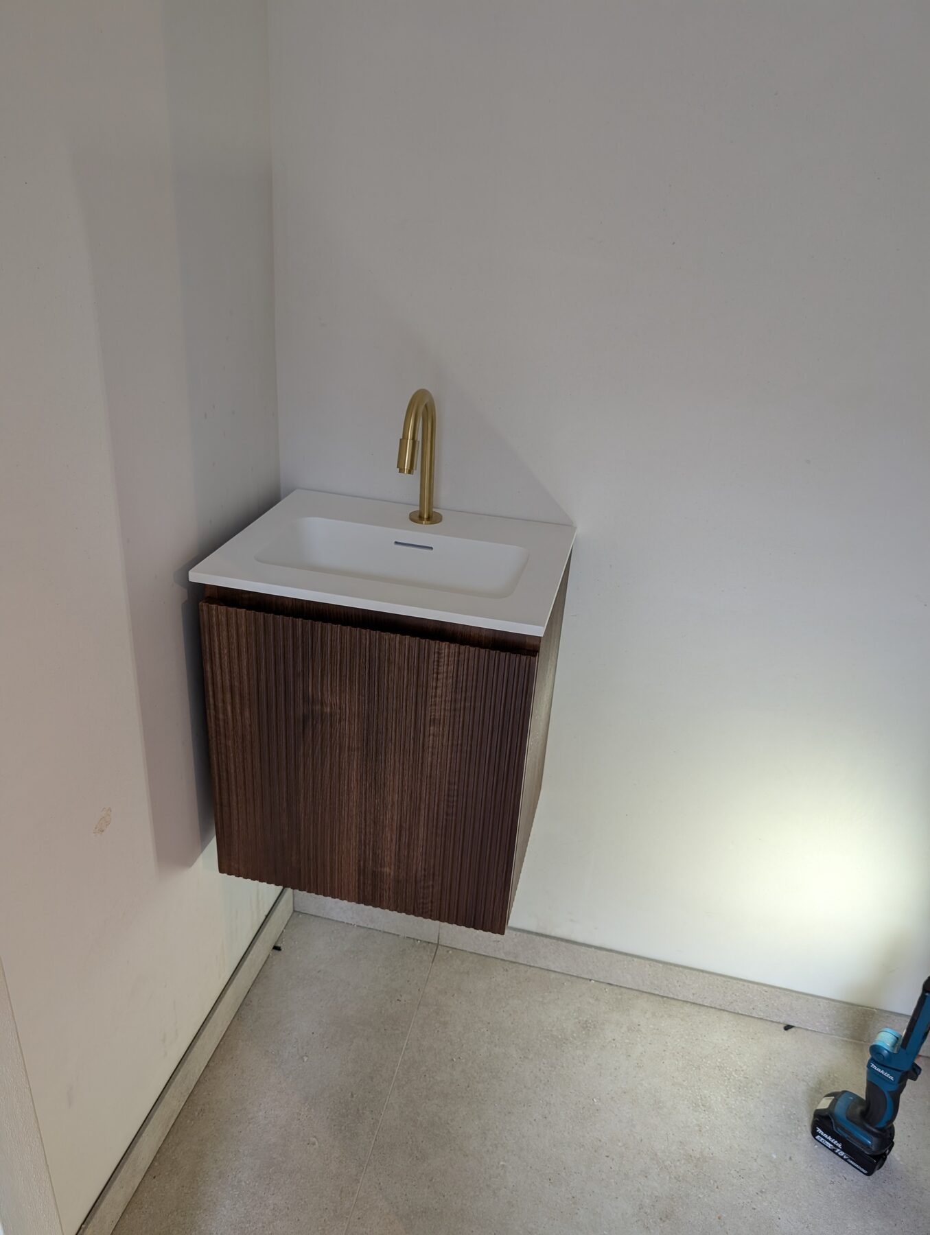 Fonteintje met houten onderkast en opbouwkraan in een toiletruimte