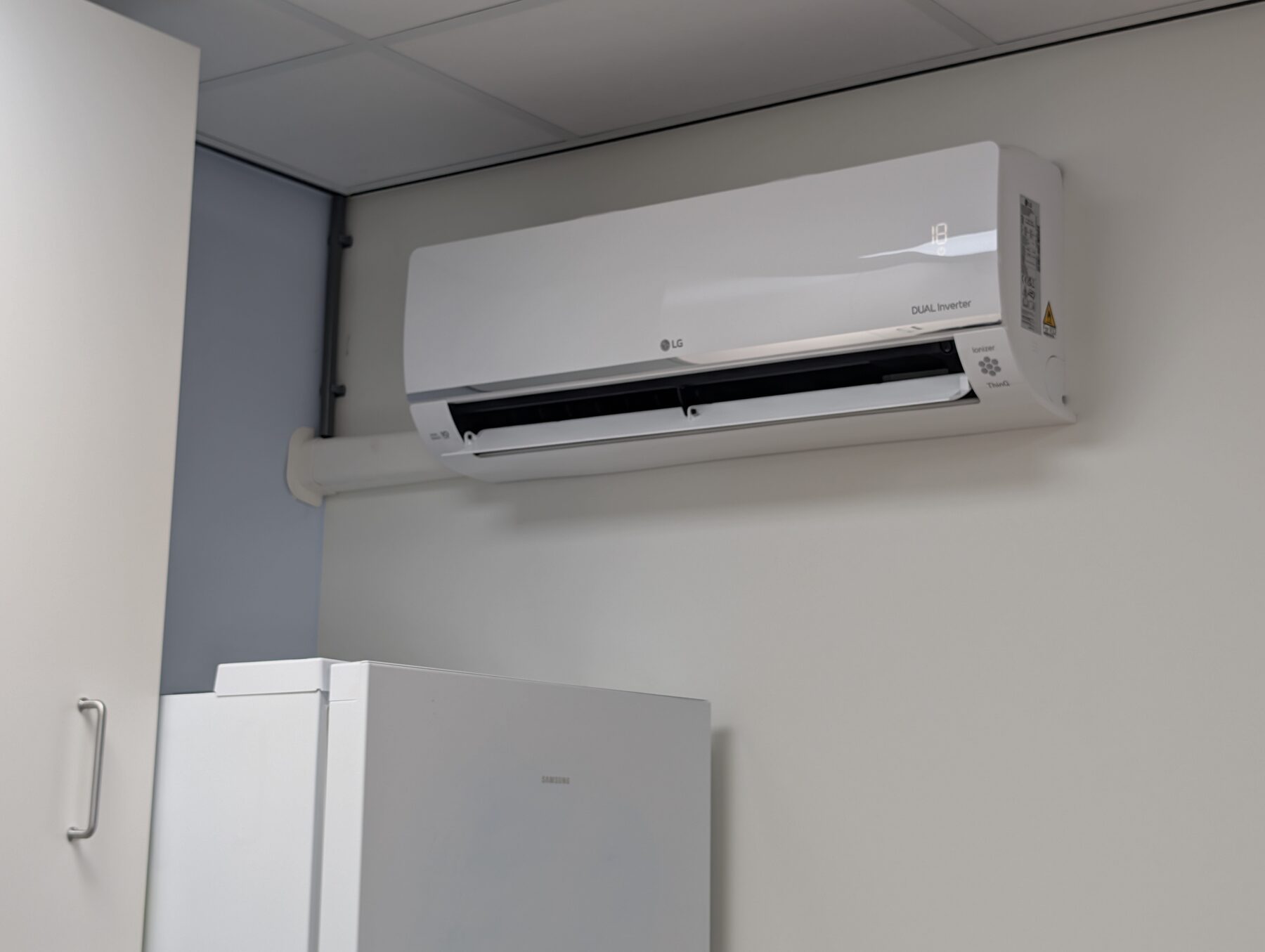 LG airco-binnenunit hoog aan de wand in een bedrijfsruimte met systeemplafond