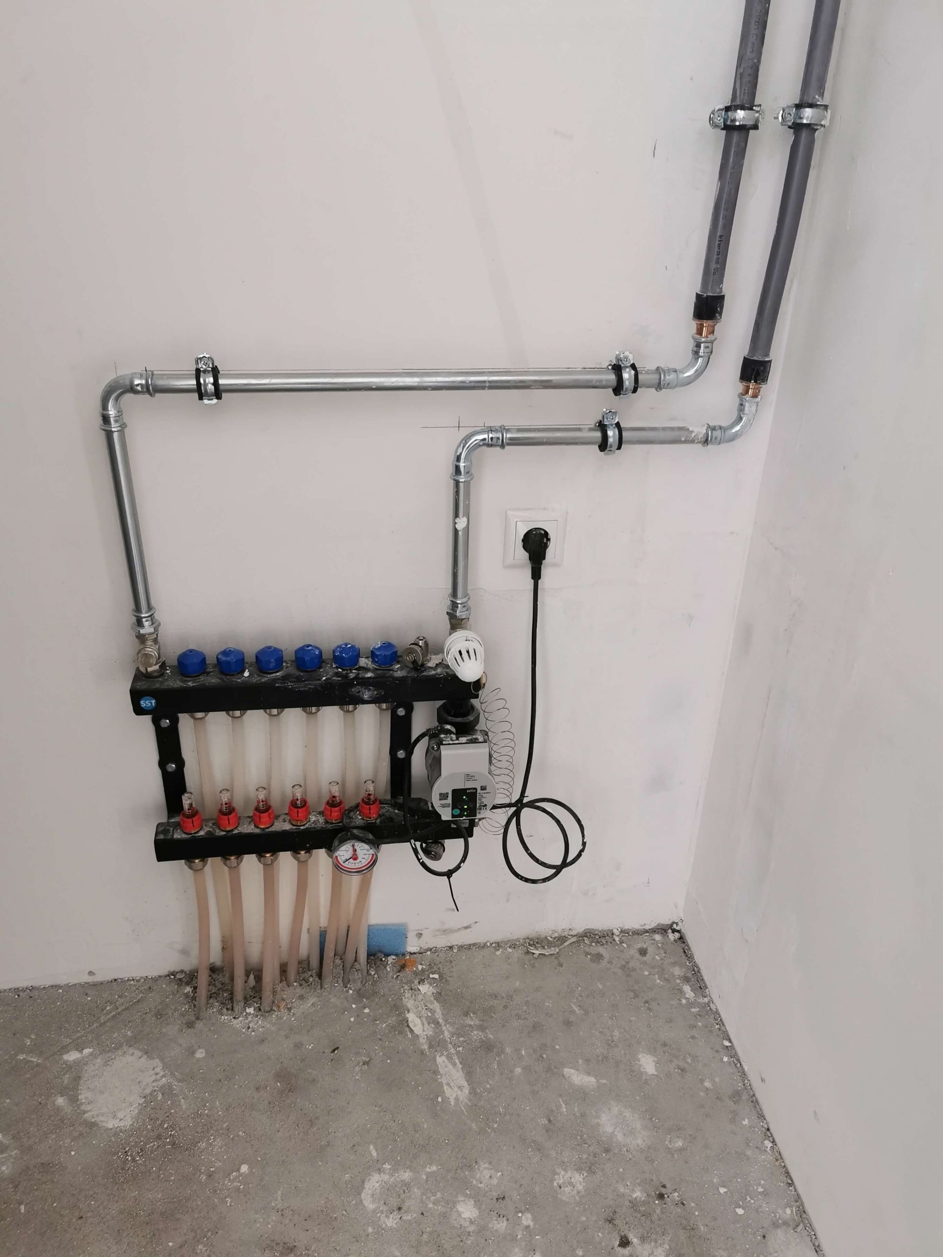 Verdeler voor vloerverwarming met circulatiepomp en stalen leidingwerk