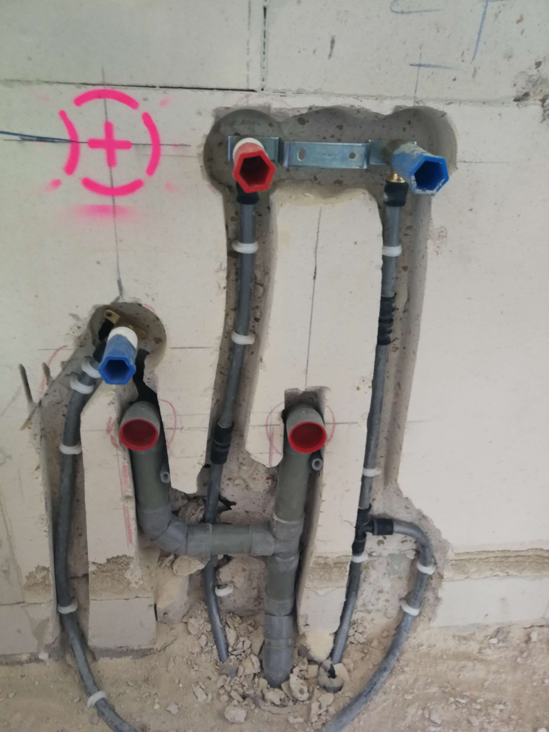 Warm- en koudwaterleidingen en afvoer ingefreesd in een wand, met de aansluitpunten afgedopt