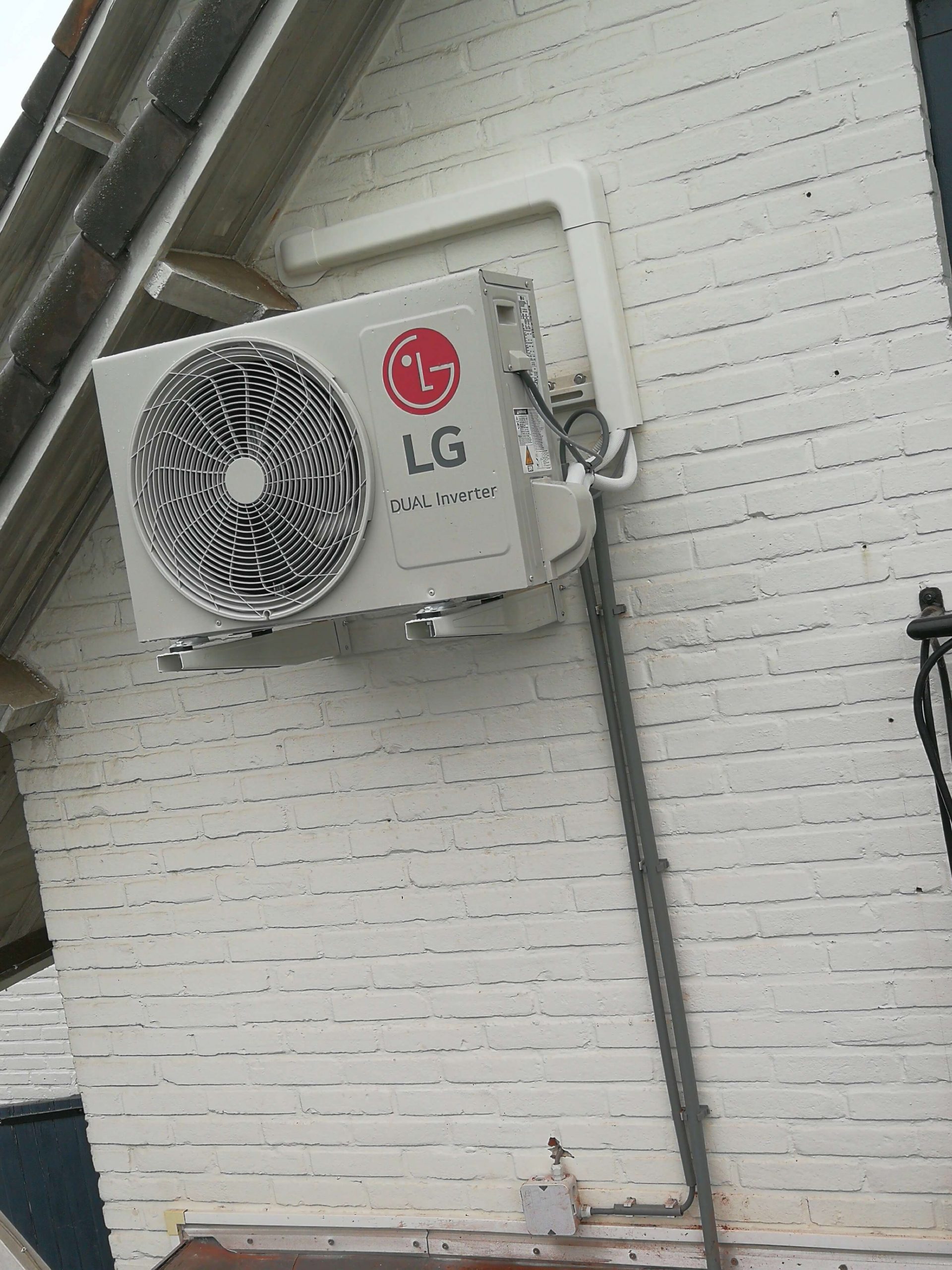 LG airco-buitenunit tegen een wit geschilderde gevel